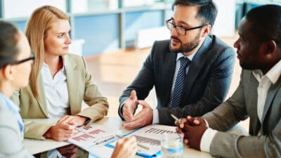 Serious businessman explaining principles of work to his colleagues at meeting