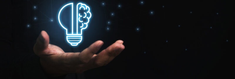 Businessman holding virtual light bulb and half brain on blue bokeh background smart thinking concept and innovative ideas inspired